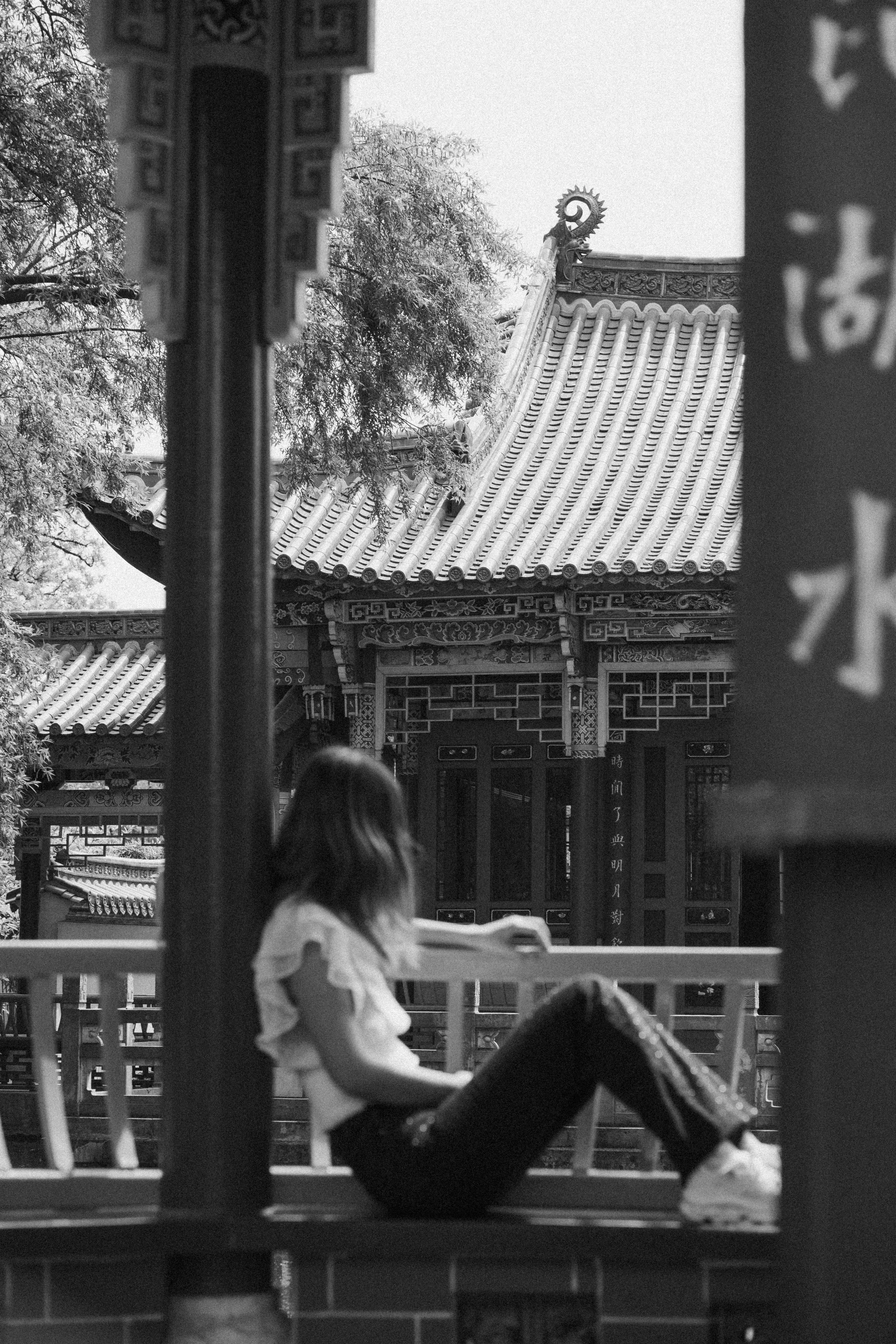A person sitting on a railing in front of traditional architecture