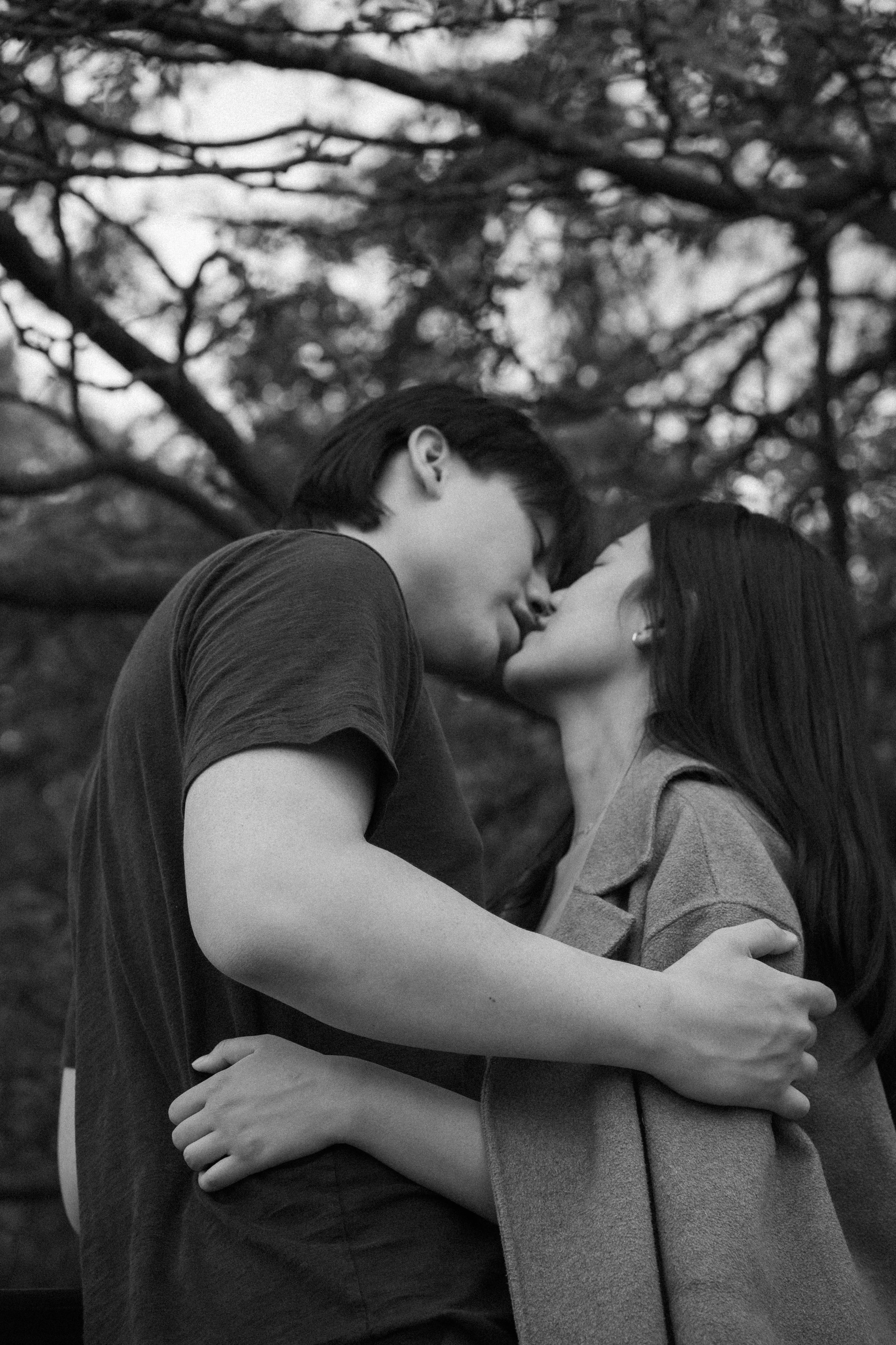 A couple kissing beneath the trees in a monochrome photograph