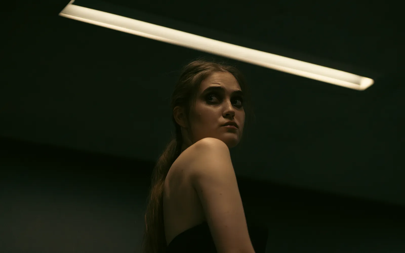 A woman looking over her shoulder in a dimly lit room